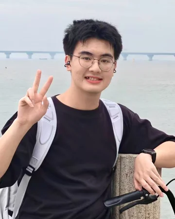Zhaoyi Tian smiling by the sea and making a peace sign.